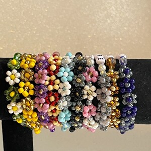 Pu&ograve; includere: Una collezione di braccialetti colorati con perline di diverse forme e colori, tra cui rosa, giallo, blu, verde e nero. I braccialetti sono impilati uno sopra l'altro e sono fatti di piccole perline rotonde.