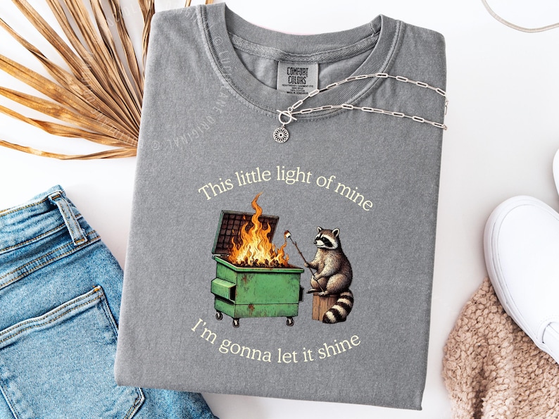 funny dumpster fire shirt, dumpster fire raccoon shirt, raccoon dumpster fire meme tee, trash panda shirt, funny raccoon graphic tee, this little light of mine parody shirt, chaotic raccoon shirt, anxiety humor shirt, funny meme t shirt, roasting marshmallow raccoon tee, comfort colors funny shirt, ironic humor tee, relatable humor shirt, chaos meme shirt, funny animal meme shirt, satirical graphic tee, unhinged raccoon tee, funny gift shirt, mental health meme tee, sarcastic tee, viral shirt