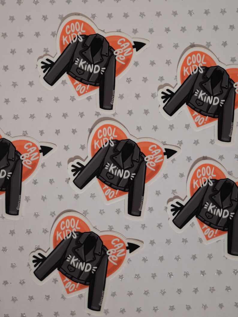 May include: Six stickers with a heart-shaped design featuring a black leather jacket with the text "COOL KIDS CAN BE KIND TOO!" in white. The heart is orange and has a white arrow pointing to the right.