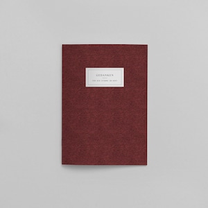 Könnte beinhalten: Ein burgunderfarbenes Notizbuch mit dem Text "GEDANKEN" und "FOR ALL THINGS TO COME TO MIND" auf einem weißen Etikett.