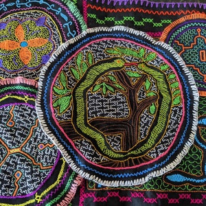 Puede incluir: Primer plano de un textil bordado de colores con múltiples diseños circulares. Los diseños presentan una variedad de colores, incluyendo rojo, verde, azul, amarillo y negro. El textil está hecho de una tela fina y está decorado con puntadas intrincadas.