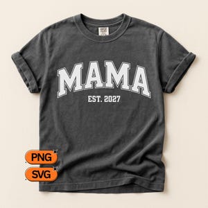 Könnte beinhalten: Ein anthrazitfarbenes Kurzarm-T-Shirt mit dem weißen, bogenförmig auf der Brust platzierten Schriftzug MAMA und dem darunter zentrierten Text EST. 2027. Das Shirt hat einen Rundhalsausschnitt und ein Markenetikett am Kragen. Zwei orangefarbene Buttons zeigen PNG und SVG.