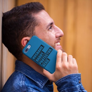 May include: A blue phone case with the text "Husband. Daddy. Protector. Hero." printed in black.