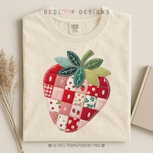 Puede incluir: Camiseta color crema con un gran diseño de fresa en patchwork. La fresa está compuesta por varios cuadrados estampados en rojo, rosa y blanco, con hojas verdes. La camiseta tiene el texto "REDLOOP DESIGNS" en la parte superior.
