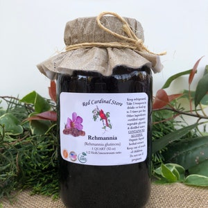 May include: A glass jar with a brown fabric lid and a label that reads "Red Cardinal Store" and "Rehmannia (Rehmannia glutinosa) 1 QUART (32 oz) 1:2 Herb/menstruum ratio NON GMO". The jar is filled with a dark liquid and is sitting on a brown burlap surface.