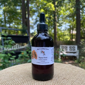 May include: A 4 ounce bottle of Papaya Seed tincture in a dark glass bottle with a dropper. The bottle has a label that says "Red Cardinal Store" and "Papaya Seed (Carica papaya)". The label also says "1:2 Herb/menstruum ratio".