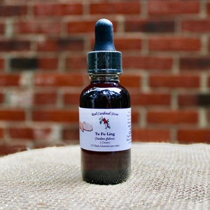 May include: A small glass bottle with a dropper filled with a dark liquid. The label reads "Red Cardinal Store" and "Tu Fu Ling (Cistanche glabra) 1 Ounce 1:2 Herb:Maceratum ratio".