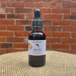 May include: A dark brown glass bottle with a dropper top, labeled "Red Cardinal Store Ginger Root (Zingiber officinale) 1 Ounce 1:2 Herb/menstruum ratio".