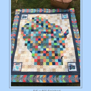 May include: A colorful patchwork quilt featuring a map of Wisconsin in the center. The quilt is 54 inches by 60 inches and is finished. The quilt is laid out on a grassy surface with a picnic basket in the background.