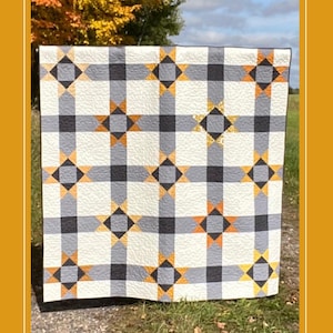 Può includere: Un modello di trapunta che presenta una trapunta di 152,4 cm x 152,4 cm con un motivo a scacchi in nero, bianco e grigio con stelle arancioni e dorate. La trapunta è esposta all'aperto su una superficie erbosa con foglie autunnali sullo sfondo. Il testo "Harvest Stars" è in alto nell'immagine. Il testo "Quilt Pattern" è sotto la trapunta. Il testo "lakegirlquilts" è sotto la trapunta. Il testo "Pattern No. 035" è sotto la trapunta.