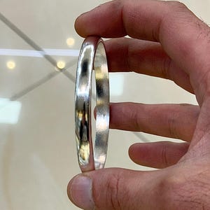 May include: A silver bangle bracelet with a smooth, polished finish.