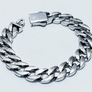 Può includere: Un braccialetto a catena curb in argento con chiusura a moschettone.