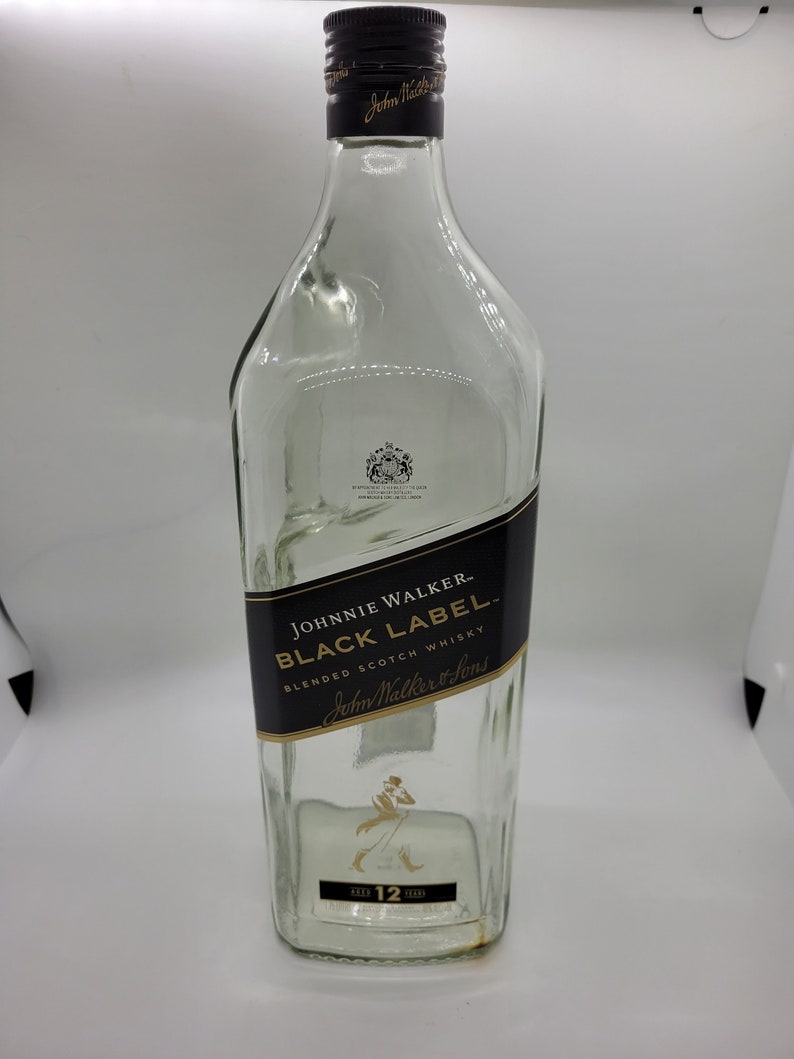 May include: A clear glass bottle of Johnnie Walker Black Label Blended Scotch Whisky. The bottle has a black label with gold lettering and a gold stag silhouette. The bottle is 12 years old.