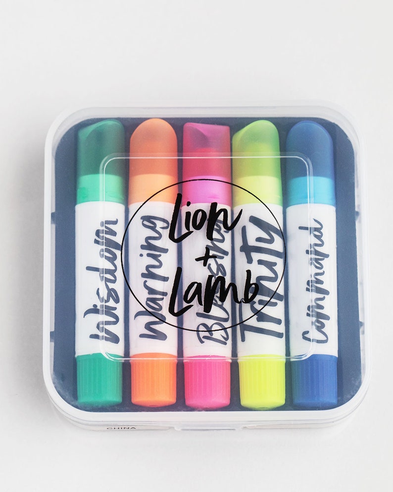 May include: A set of six colorful highlighters in a clear plastic case. The highlighters are labeled with the words "In this dawn", "Morning", "Lion + Lamb", "Truth", and "Come in faith".