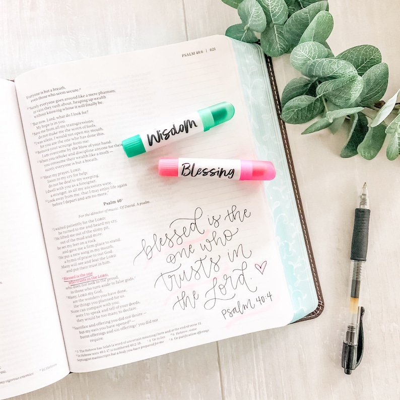 May include: A close-up of an open Bible with the words "Blessed is the one who trusts in the Lord" highlighted in black ink. The words "Wisdom" and "Blessing" are written on pink and green highlighters.