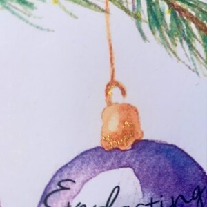 May include: A purple Christmas ornament with gold glitter hanging from a branch. The ornament has the word "Everlasting" written on it.