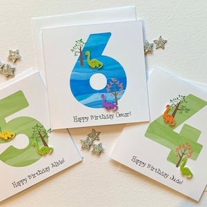 Carte d'anniversaire personnalisée numérotée avec un dinosaure. Illustration aquarelle de l'époque agrémentée de deux adorables boutons de dinosaure en bois.