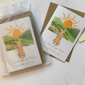 May include: Two watercolor greeting cards with a rabbit and a sun illustration. The cards have the text "A little note from Karen to brighten your day..."