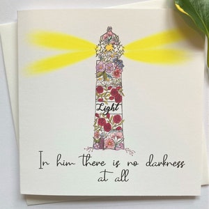 Belle carte de versets bibliques à encourager avec le verset "En lui il n'y a pas de ténèbres du tout" illustré d'un phare.