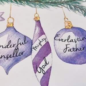 May include: Three purple and white Christmas ornaments with gold tops. The ornaments are decorated with the words "Wonderful Counsellor", "Mighty God", and "Everlasting Father".