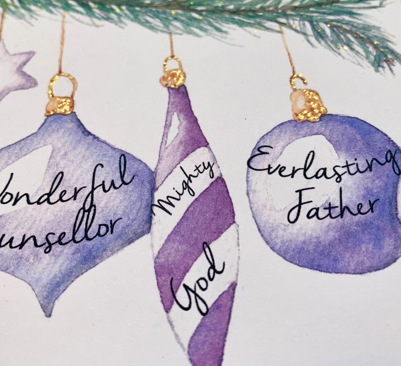 May include: Three purple and white Christmas ornaments with gold tops. The ornaments are decorated with the words "Wonderful Counsellor", "Mighty God", and "Everlasting Father".