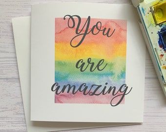 May include: A card with a rainbow watercolour background and the text "You are amazing" in black cursive font.