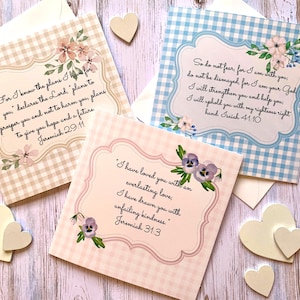 May include: Three greeting cards with floral designs and Bible verses. One card features a beige gingham pattern, another a blue gingham pattern, and the third a pink gingham pattern. Each card has a decorative border and a white envelope.
