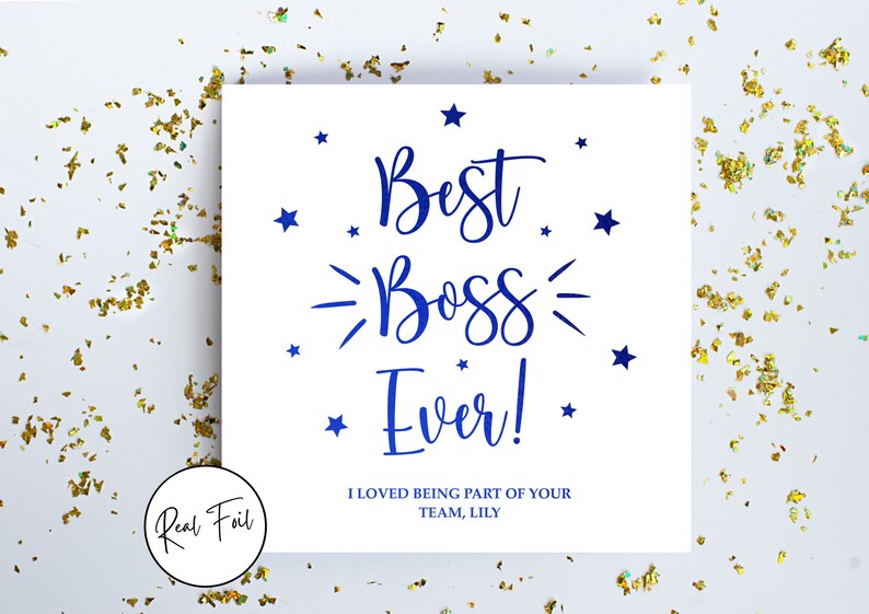 May include: A square white greeting card featuring the blue text "Best Boss Ever!" in a script font, surrounded by small blue stars. Below the main text, the card reads "I LOVED BEING PART OF YOUR TEAM, LILY" in blue capital letters. A circular badge reads "Real Foil".
