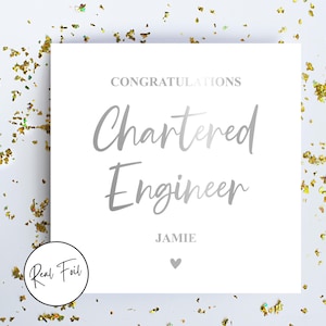 May include: A white card with silver text reading "CONGRATULATIONS Chartered Engineer" and the name "Jamie" below, with a heart symbol. Gold foil confetti is scattered around the card. A "Real Foil" logo is visible.