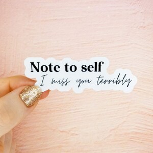 May include: White sticker with black text that reads "Note to self I miss you terribly".