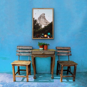 Pu&ograve; includere: Due sedie di legno con un tavolo di legno davanti a un muro blu. Un quadro incorniciato di una montagna con un edificio in cima &egrave; appeso al muro.