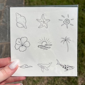 May include: A sheet of temporary tattoos with a variety of summer-themed designs, including a seashell, starfish, sun, hibiscus flower, palm tree, whale, shark, and waves.