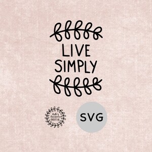 Puede incluir: Diseño de corte SVG en blanco y negro con el texto "Live Simply" rodeado de elementos florales estilizados. El diseño es perfecto para crear manualidades, decoración del hogar y mucho más.