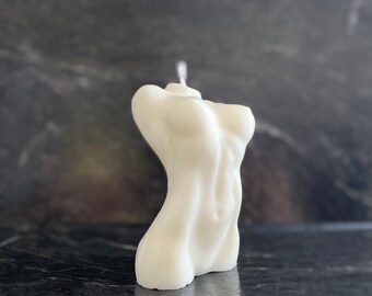 May include: A white candle shaped like a human torso. The candle has a single wick and is made of a smooth, matte finish.