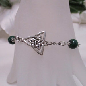 May include: A silver Celtic knot charm bracelet with green malachite beads.