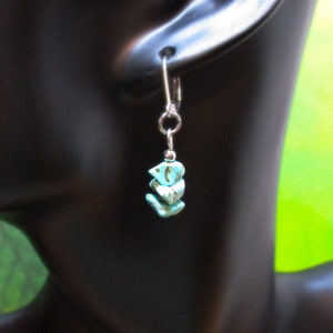 May include: Silver dangle earrings with three turquoise blue stones in a triangular shape.