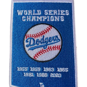 May include: Blue and white embroidered patch with the words "World Series Champions" and "Dodgers" in white. The patch also features a baseball with red stitching and the years "1955 1959 1963 1965 1981 1988 2020" and "LA" in white.