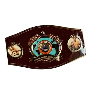May include: A brown leather World Super Champion boxing belt with gold detailing. The belt features a central emblem of a globe with the WBO logo and two circular portraits of a boxer.