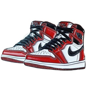 May include: A pair of red and white high-top sneakers with black laces and a black Nike swoosh logo. The sneakers have a white midsole and a red outsole.
