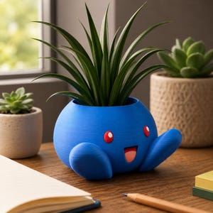 May include: A blue, cartoon-like planter with a smiling face, red eyes, and outstretched arms, holding a green plant. The planter is on a wooden surface, with other potted plants in the background.