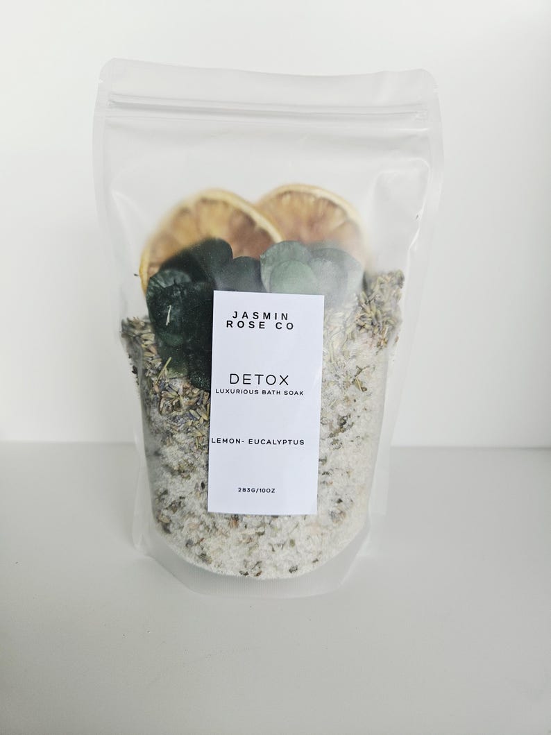 May include: A clear, resealable bag filled with bath soak. The bag contains dried lemon slices, green leaves, and a mix of salts and herbs. A white label reads "JASMIN ROSE CO DETOX LUXURIOUS BATH SOAK LEMON - EUCALYPTUS".