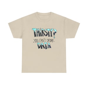 Könnte beinhalten: Ein beiges T-Shirt mit kurzen Ärmeln und dem Text "THIRSTY? YOU CAN'T DRINK DATA" in einer stilisierten, tropfenden Schriftart. Die Buchstaben verlaufen von einem dunklen Marineblau an der Basis zu einem hellen Cyanblau oben, mit kleinen Wassertropfen.