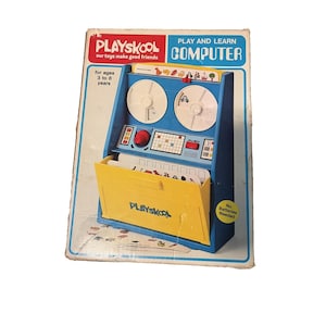 May include: A vintage Playskool Play and Learn Computer toy box featuring a blue and yellow plastic console with two white circular reels, a red knob, a grid of buttons, and a yellow front panel with the Playskool logo for ages 3 to 8 years.