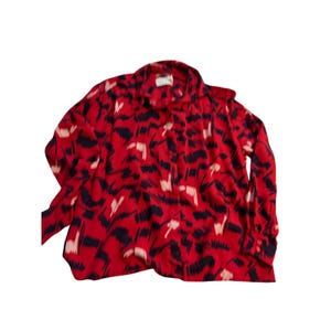 May include: A red button-down shirt with a bold abstract pattern in navy and cream. The long-sleeved shirt has a classic collar and buttoned cuffs. The fabric appears to be lightweight.