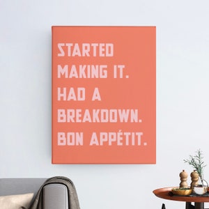 May include: A coral orange canvas print with the text "STARTED MAKING IT. HAD A BREAKDOWN. BON APPÉTIT." in pink.