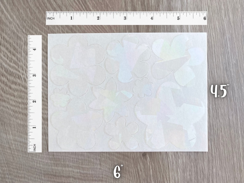 May include: A sheet of iridescent vinyl stickers featuring various flower shapes. The sheet measures 6 inches by 4.5 inches.