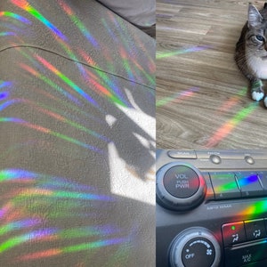 May include: A cat sits on a wooden floor with rainbow light reflecting off the surface. The light also reflects off a car dashboard with the words "VOL PUSH PWR" and "A/C" visible.