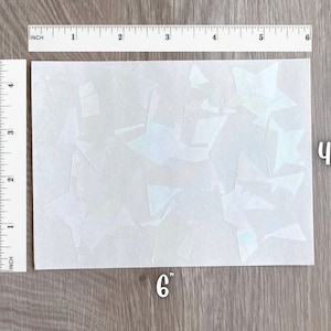 May include: A sheet of white iridescent vinyl with multiple star shapes cut out. The sheet measures 6 inches by 4.5 inches.