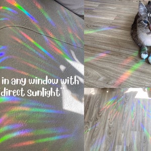 May include: A rainbow prism window cling creates colorful light patterns on a wooden floor and a gray fabric surface. The text "Place in any window with direct sunlight" is visible in the image.