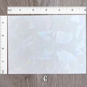 May include: A sheet of iridescent vinyl with a variety of geometric shapes cut out. The sheet measures 6 inches by 4.5 inches.